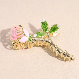 Detail van de haarklem met roze emaille roos en goudkleurige metalen tanden