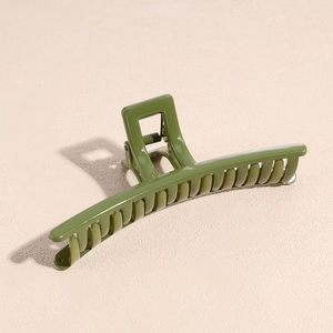 Primo piano di una pinza per capelli verde oliva lucida su uno sfondo neutro testurizzato
