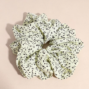 Vue détaillée d'un chouchou beige à pois noirs avec une texture en mousseline plissée