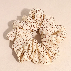 Texture détaillée d'un grand chouchou beige avec motif léopard marron moucheté
