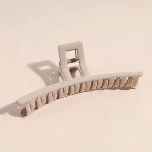Dettaglio della grande pinza per capelli beige con superficie liscia e molla in metallo