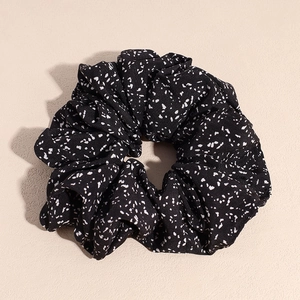 Gros plan détaillé d'un chouchou en tissu noir à pois blancs avec texture froissée