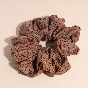 Macro d'un chouchou marron avec des motifs mouchetés noirs et une texture de tissu doux