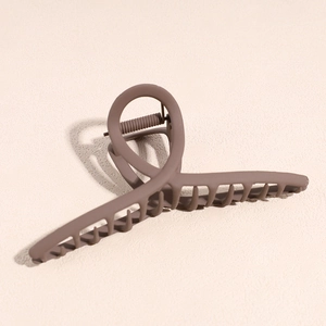 Gros plan sur la pince à cheveux marron mat avec design en spirale croisée et ressort en métal