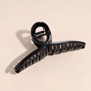 Dettaglio di un fermaglio per capelli nero lucido con design a spirale e molla argentata