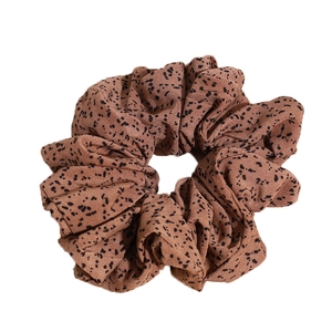 Grand chouchou beige à motifs mouchetés noirs avec une texture plissée en tissu