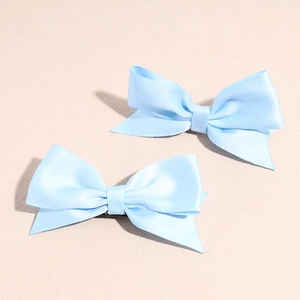 Macro view of light blue satin bow hair clips with soft silk texture and dual wings