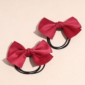 Détail de chouchous à nœuds en satin rouge avec élastiques haute résistance sur fond
