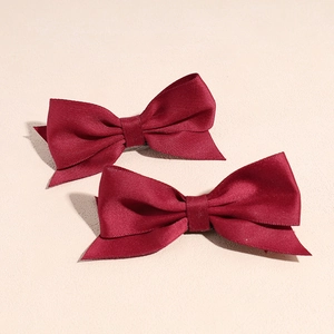 Pair of wine red satin bow hair clips shown with elegant silky texture and detail