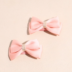 Détail de deux barrettes à cheveux en ruban de satin rose avec accents de fils dorés