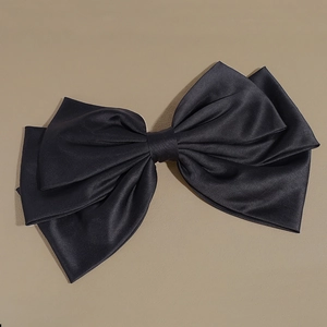 Detailed view of the layered structure and smooth satin texture of the oversized black bow clip