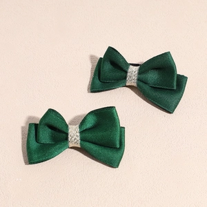 Détail de deux barrettes à nœuds en satin vert foncé avec centre élégant en fil doré