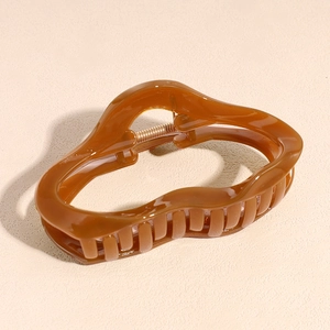 Macro shot of an amber irregular acetate hair claw clip with a glossy finish and metal spring