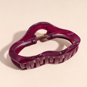 Detail of burgundy translucent acetate hair claw clip with golden metal spring