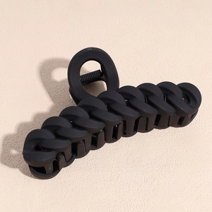 Macro detail of a black matte chain-style hair claw clip with a secure metal spring