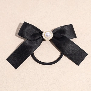 Close-up of black satin bow hair tie with elegant faux pearl centerpiece detail