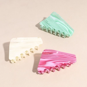Three acetate hair claw clips with marble pattern in pink, green, and beige colors