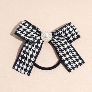 Detailed macro view of houndstooth bow hair tie with large central white pearl accent