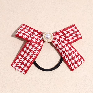 Detail of red houndstooth bow hair tie with center pearl and gold-toned embellishment