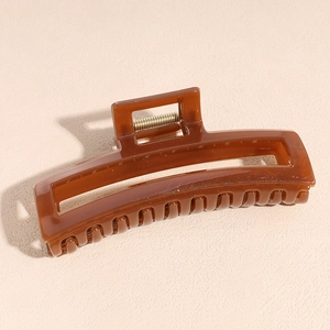 Detail of amber acetate hair claw clip showing translucent texture and gold metal spring