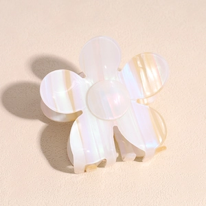 Detail view of pearlescent flower claw clip with elegant striped acetate texture