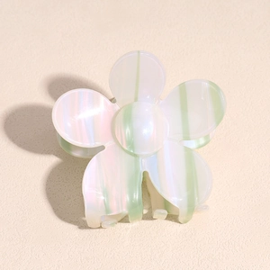 Macro view of flower-shaped hair claw clip with pearlescent white and green stripe texture