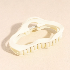 Close-up of a wavy cream-colored hair claw clip with a visible metal spring