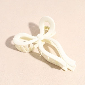 Détail d'une pince à cheveux nœud blanc crème avec finition mate et ressort doré