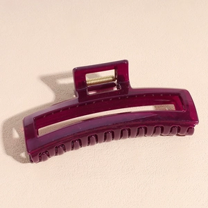 Detail view of large dark purple translucent acetate hair claw clip with golden spring