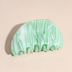 Detailed macro view of mint green marble acetate hair claw with polished smooth teeth