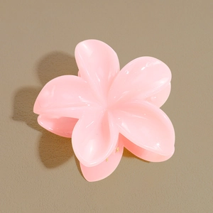 Détail d'une pince à cheveux en résine rose clair en forme de fleur de frangipanier polie