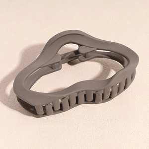 Detail of matte coffee brown hair claw clip with irregular wavy hollow design
