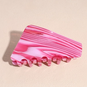 Detail showing the pink and white striped marble texture of the acetate hair claw clip