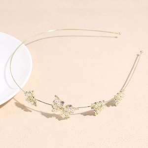 Détail d'un serre-tête en alliage doré orné de papillons en perles et strass brillants