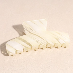 Detail of a large cream and olive green striped acetate shark hair claw clip accessory