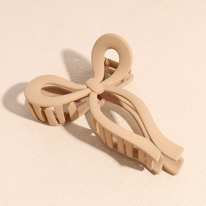 Detail view of large matte khaki hair claw clip with crossed bow design and metal spring