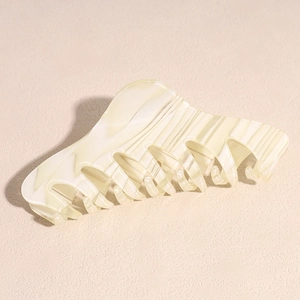 Detail view of large cream striped acetate hair claw clip with wavy teeth design