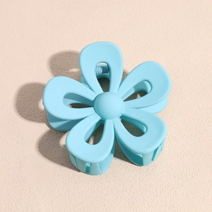 Dettaglio macro di una pinza per capelli a fiore azzurro opaco con molla in metallo