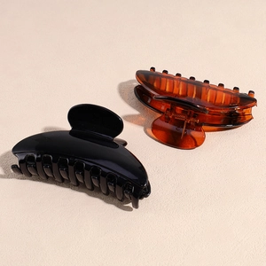 Set of black and amber acrylic hair claw clips for thick hair shown on a beige surface
