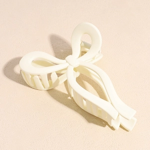 Detailed close-up of matte cream-colored butterfly hair claw clip with metal spring