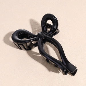 Gros plan d'une pince à cheveux nœud noir brillant avec grandes dents pour un style chic