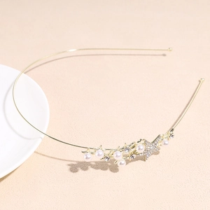 Détail d'un serre-tête doré fin orné de perles blanches et d'une étoile en strass