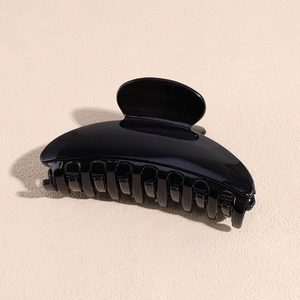 Close-up of a glossy black acrylic hair claw clip with a sleek curved semi-circular design