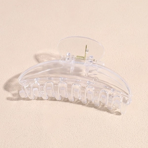 Macro detail of curved acrylic hair claw clip with golden metal spring and clear texture