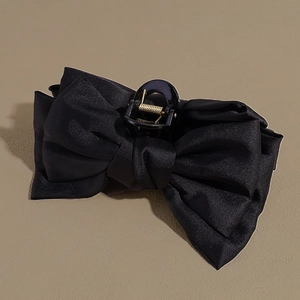Close-up of black satin bow hair claw clip with glossy texture and metal spring detail