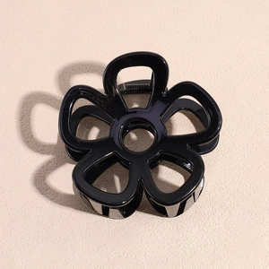 Macro view of a black hollowed-out flower hair claw clip with a glossy finish