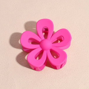 Vista dall'alto della molletta per capelli a fiore rosa opaco su sfondo beige