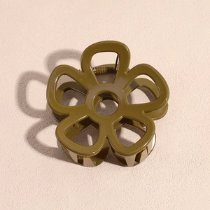 Overhead shot of an olive green flower hair claw clip with a detailed hollow design