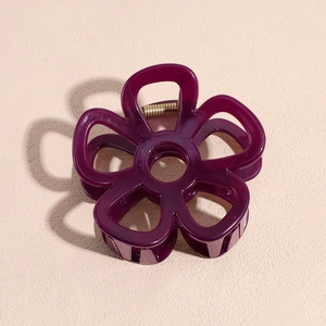 Detailed close-up of dark purple flower hair claw clip with golden metal spring