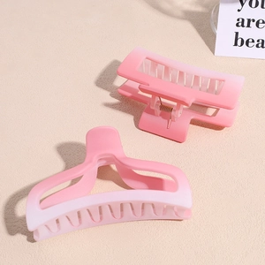 Detail view of pink and white gradient hair claws with a smooth matte finish and metal spring
